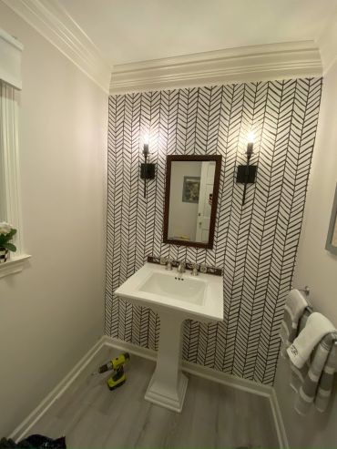 Modern bathroom with patterned wallpaper and pedestal sink.