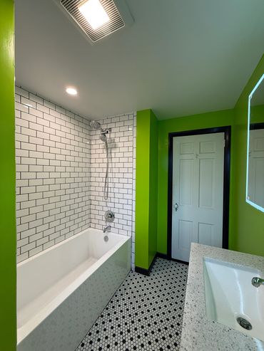Green bathroom with white subway tiles and hexagonal floor tiles.