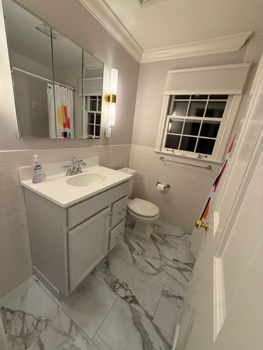 Modern bathroom with marble tile floor and white cabinetry.
