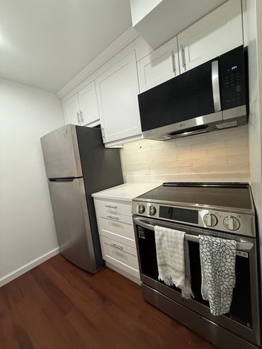 Modern kitchen with stainless steel appliances and white cabinets.