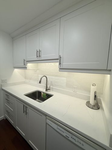 Modern white kitchen countertop with sink and cabinets.