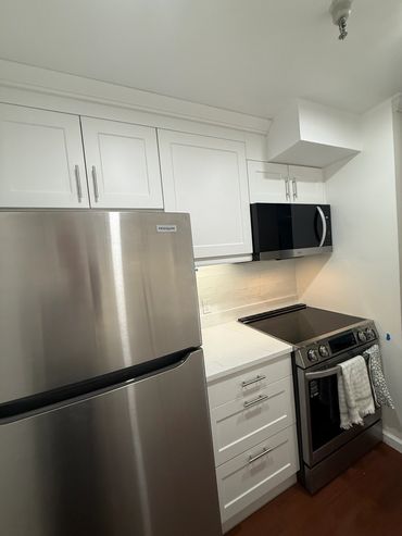 Modern kitchen with stainless steel appliances and white cabinets.