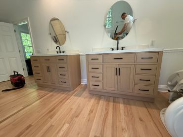Modern bathroom with wooden vanities and oval mirrors.