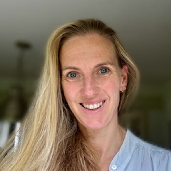 Smiling woman with long blonde hair in a light blue shirt.