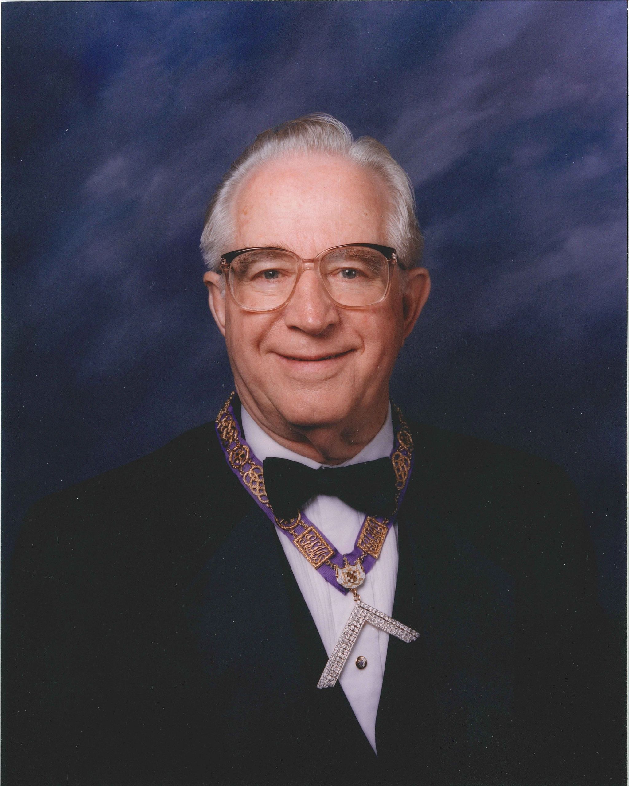 Elderly man in formal attire with a decorative chain and bow tie.