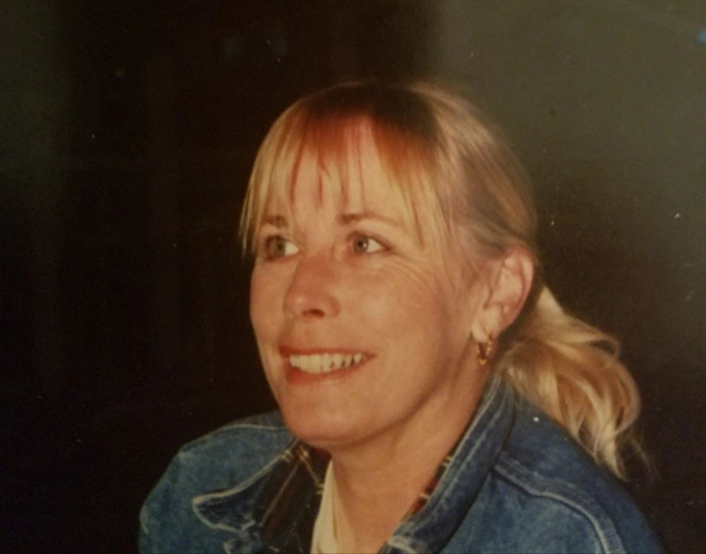Smiling woman with blonde hair in a denim jacket.