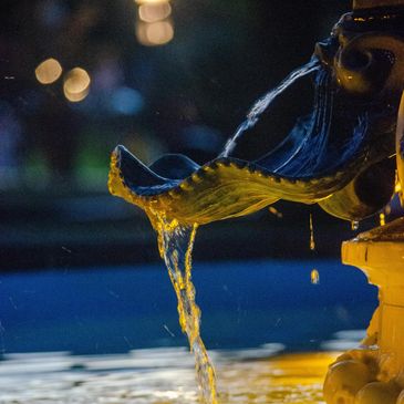 Water flowing from a decorative outdoor fountain at night.