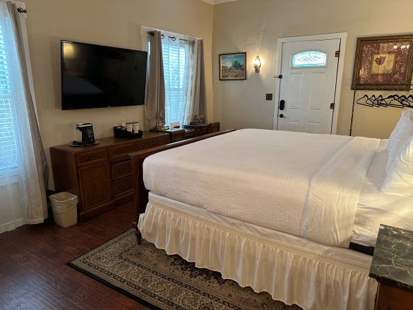 Cozy bedroom with a large bed, TV, and wooden furniture.