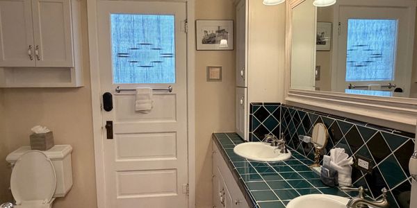 Bathroom with teal tiled countertop and dual sinks.