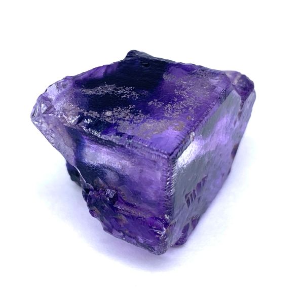 A cube-shaped purple crystal with rough edges.