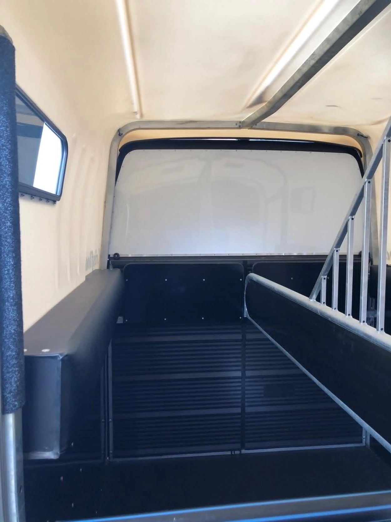 Interior of a vehicle with padded seating and metal railings.