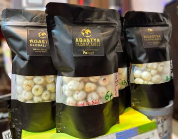 Black packages of Agastya Global Asile snacks on a store shelf.