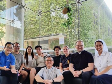 Group photo of diverse people smiling indoors.