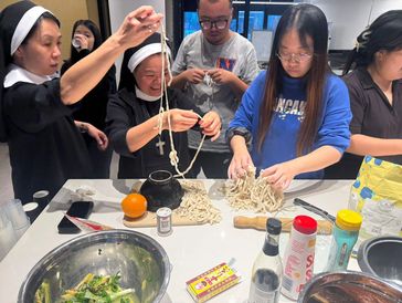 Group making noodles together in a kitchen.