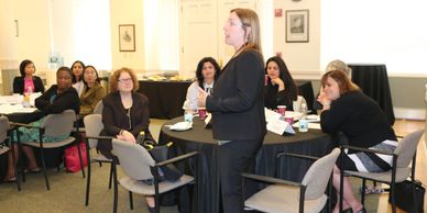 Janet Elie Faulkner standing to present at a professional meeting for attorneys seated at tables