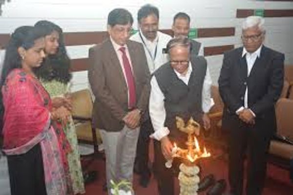 Group lighting a ceremonial lamp in a formal setting.