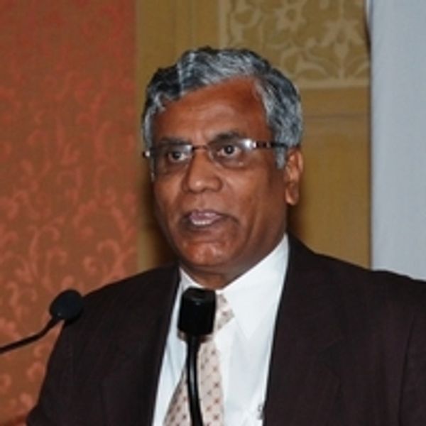 Man in suit speaking at a microphone indoors.