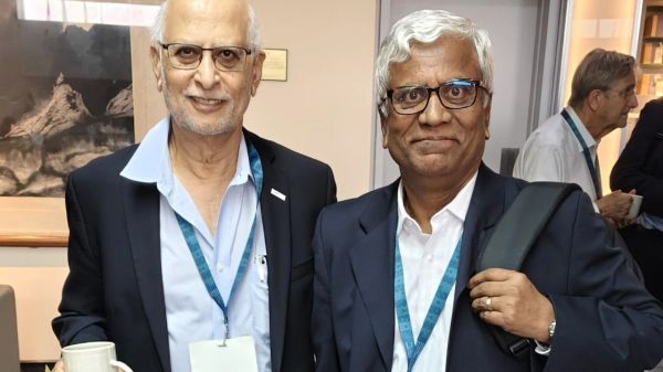 Two elderly men in suits at a formal event, smiling at the camera.