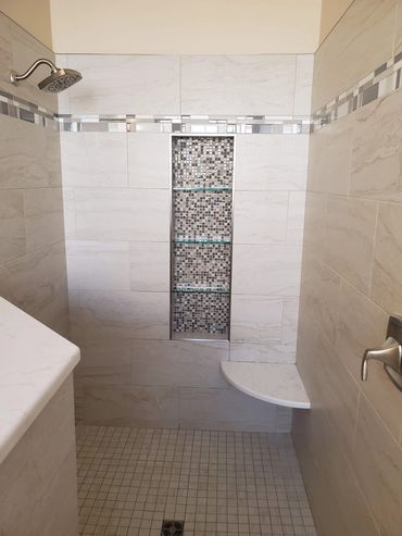 Modern bathroom with tiled shower and built-in shelf.