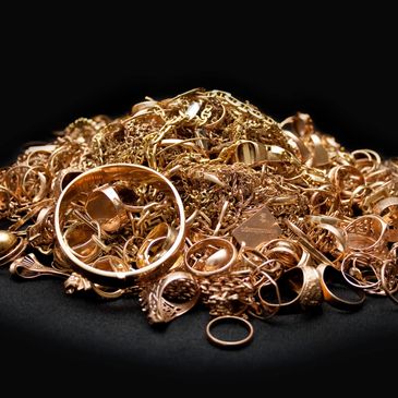 Pile of assorted gold jewelry against a black background.