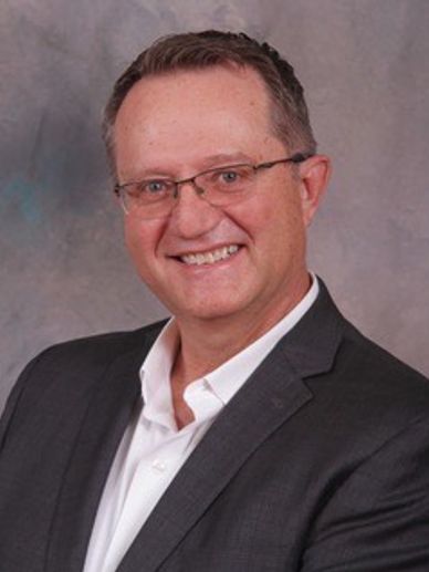 Smiling man in glasses and suit.