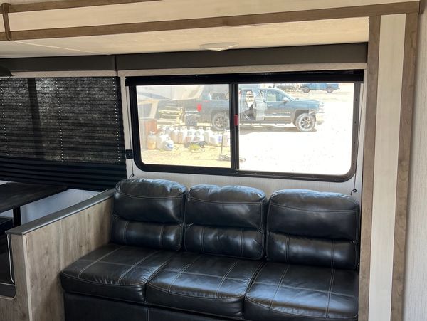 Black leather couch inside an RV with a window showing outdoor scene.