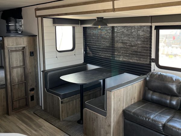 Compact dining area with black cushioned benches and wooden accents inside an RV.