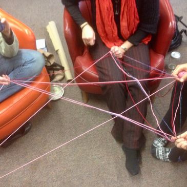 Group of people holding interconnected strands of yarn