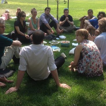 Group of people sitting on grass eating and talking