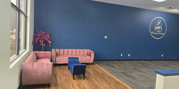 Modern lounge area with pink sofas, blue stools, and a blue accent wall.