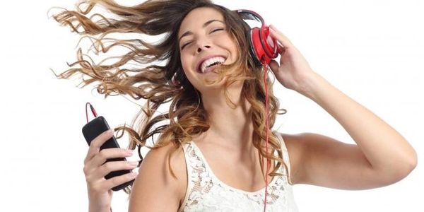 Young woman enjoying music with red headphones and a phone.