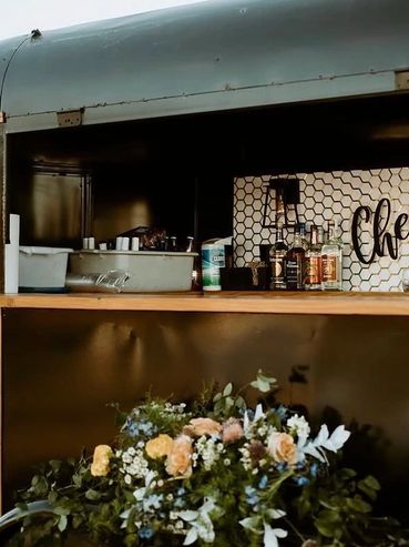 A cozy bar setup with bottles and floral decoration.
