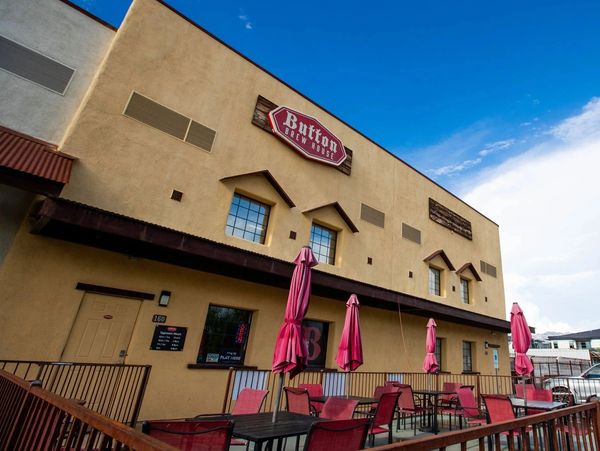 Outdoor seating area with red umbrellas at Burton Brew House under a clear blue sky.