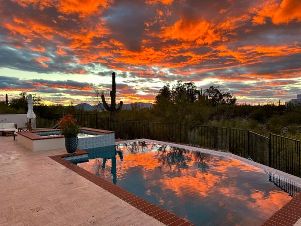Sunset reflecting on an infinity pool surrounded by desert landscape.
