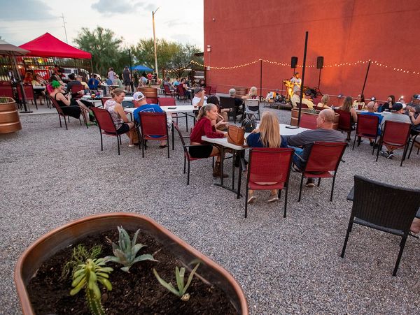 Outdoor evening event with people seated, enjoying live music near a red building.