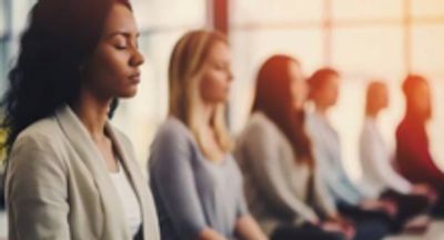 A group of people meditating in a calm, sunlit room.