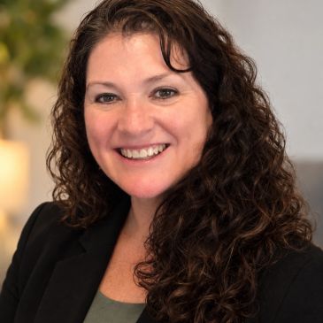 Smiling woman with curly hair in professional setting.