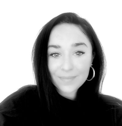 Black and white close-up portrait of a smiling woman with hoop earrings.