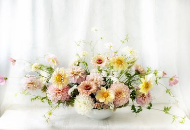 Elegant bouquet of soft pastel flowers in a white vase.
