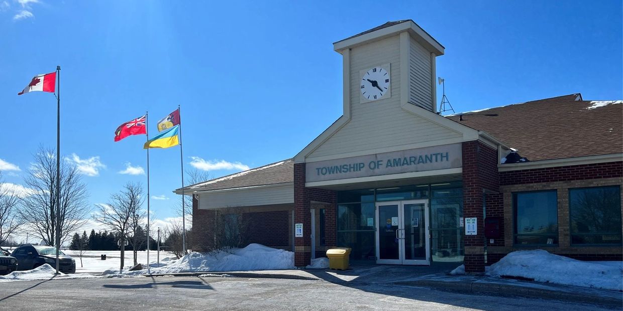 Township of Amaranth building with flags and snow under a clear blue sky.