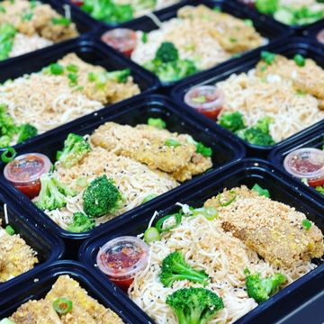 Meal prep containers with noodles, broccoli, and breaded cutlets.