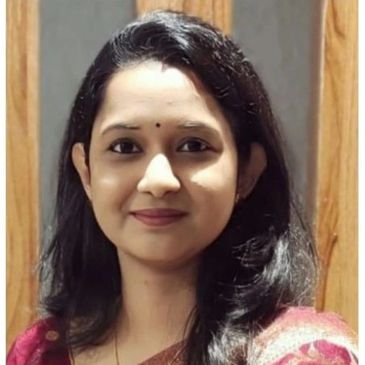 Portrait of a smiling woman with long hair and a small bindi.