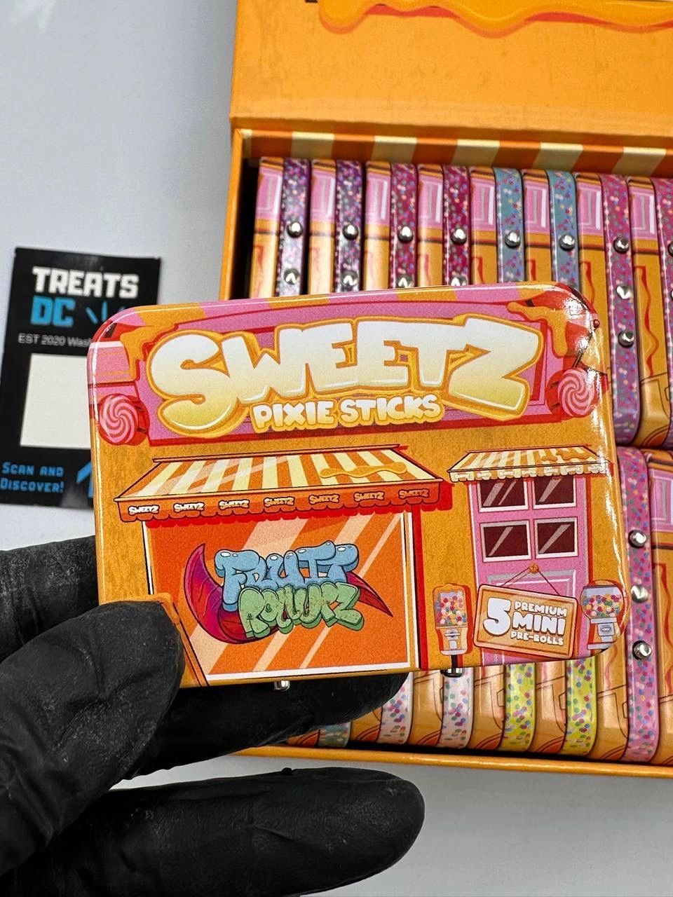 Hand holding a Sweetz Pixie Sticks candy tin.