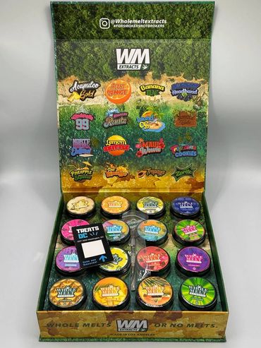 Display of Whole Melts cannabis extract containers with various strain labels.