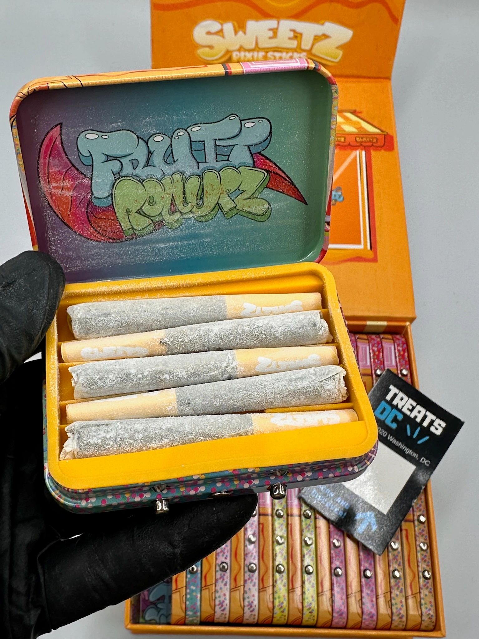 A tin box labeled "Fruitz Powerz" holding rolled cigarettes.
