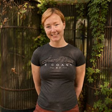 Smiling woman in a dark t-shirt outdoors.
