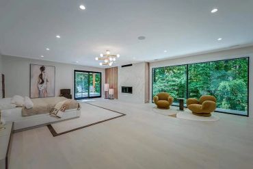 Spacious modern bedroom with large windows and stylish seating.