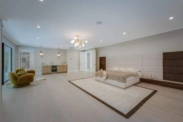 Spacious modern bedroom with minimalist design and cozy seating.