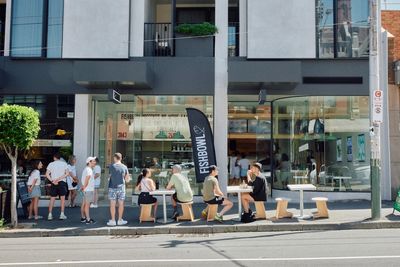 People wait and sit outside Fishbowl cafe on a sunny day.