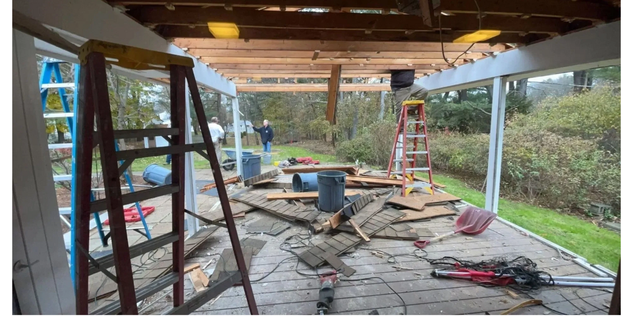Carpentry job in progress with exposed wooden beams, ladders, tools, and construction debris.